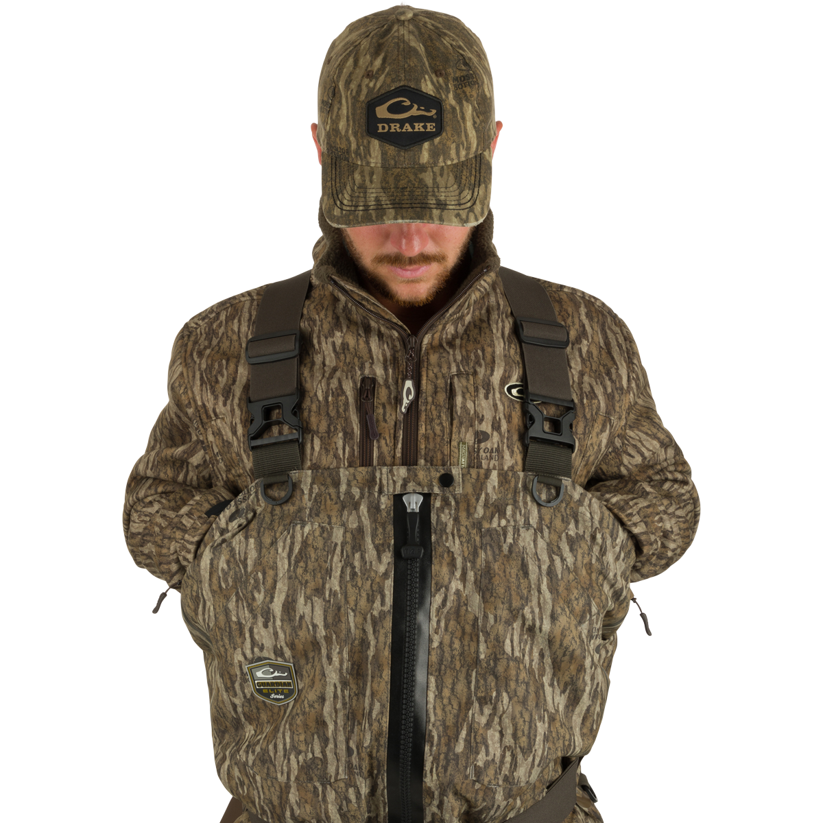 Man wearing the Insulated Guardian Elite HND Front Zip Wader in Mossy Oak Shadow Grass Habitat, featuring a camo jacket and hat, showcasing durability and warmth for hunting.